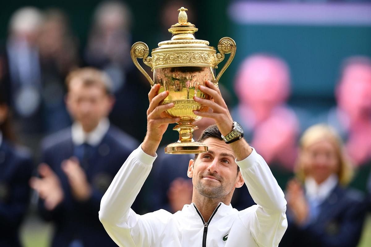 Novak Djokovic raises the winner's trophy after beating Switzerland's Roger Federer during their men's singles final on day thirteen of the 2019 Wimbledon Championships at The All England Lawn Tennis Club in Wimbledon, southwest London, on July 14, 2019.