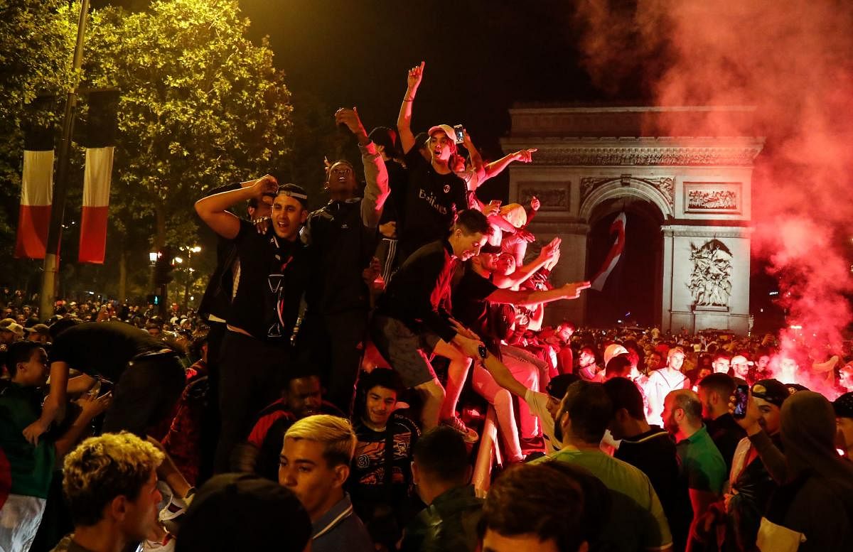 Algeria supporters celebrate after Algeria won the 2019 Africa Cup of Nations (CAN) semi-final football match against Nigeria, on the Champs-Elysee avenue in Paris on July 14, 2019. - Riyad Mahrez rifled in a stoppage-time free-kick to earn Algeria a dram