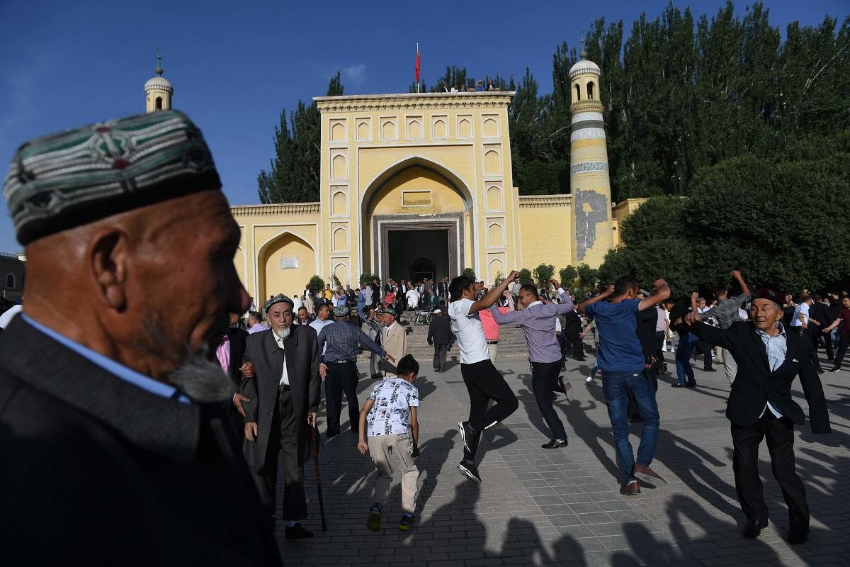 This photo taken on June 5, 2019 shows Uighur men dancing after Eid al-Fitr prayers, marking the end of Ramadan, outside the Id Kah mosque in Kashgar, in China's western Xinjiang region. - In China's Xinjiang, a northwest region tightly controlled by poli