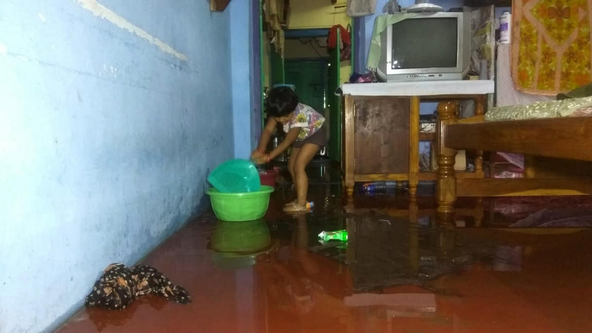 A child drains out water after Sunday night showers flooded her house at Madhavnagar in Karwar.