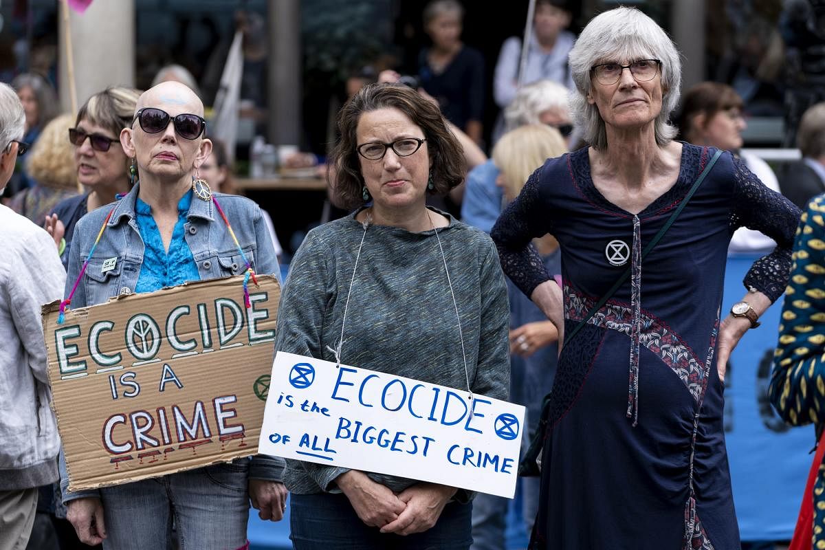 Demonstrators hold a placards as "Extinction Rebellion", the climate environmental activist group, protests outside of The Royal Courts of Justice on The Strand in central London in London. (AFP Photo)