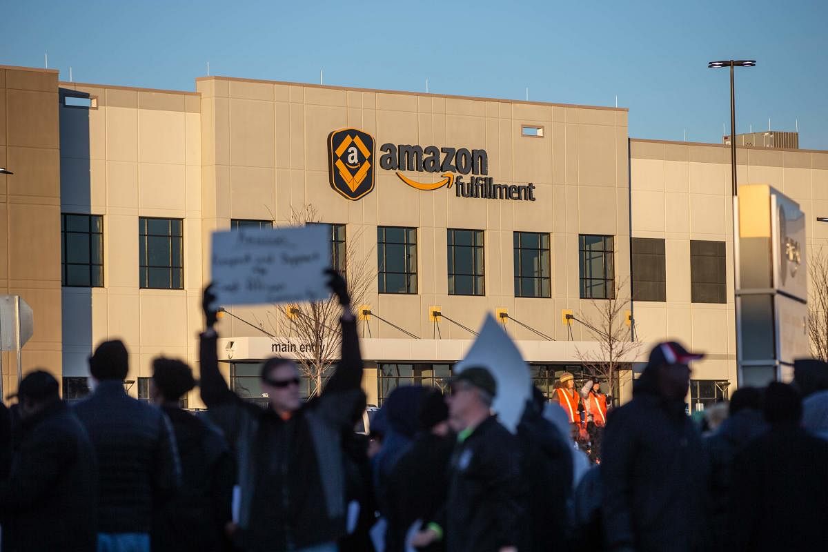 Demonstrators shout slogans and hold placards during a protest at the Amazon fulfillment center in Shakopee, Minnesota last year (AFP File Photo)