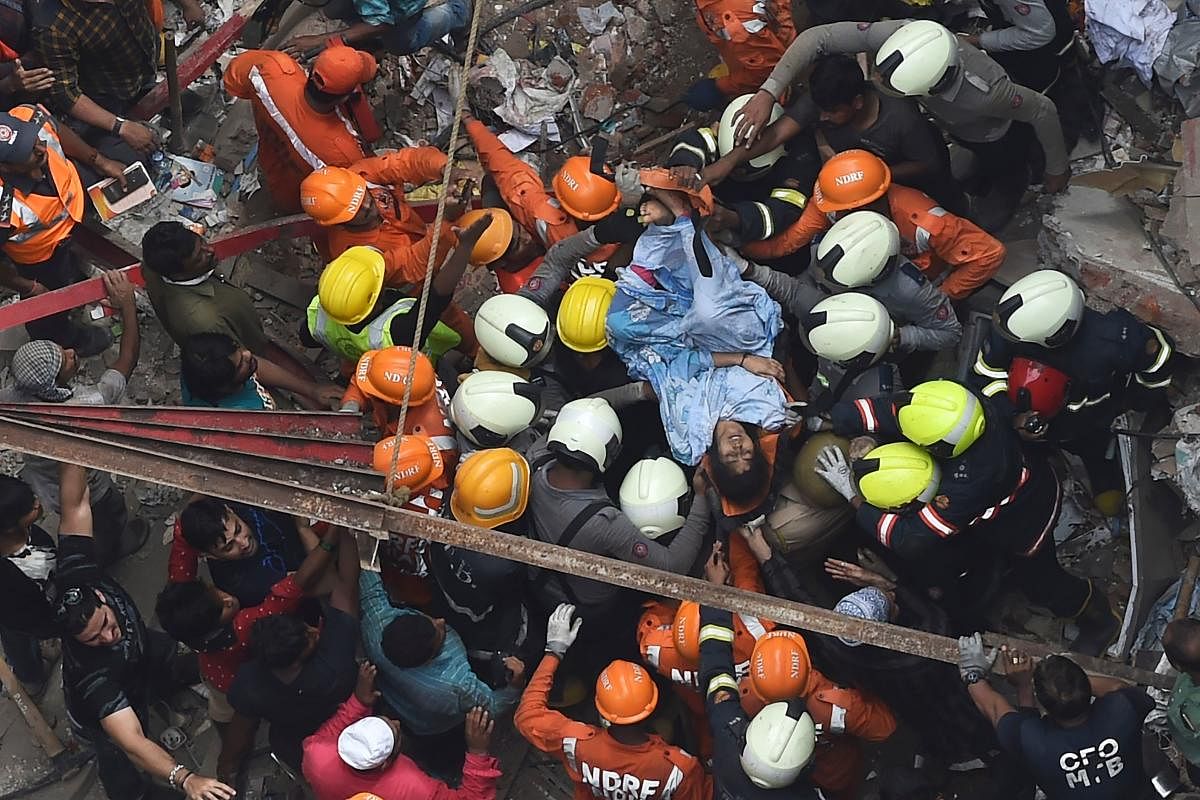 National Disaster Response Force and Indian fire brigade personnel rescue a survivor from after a building collapsed in Mumbai. (AFP Photo)