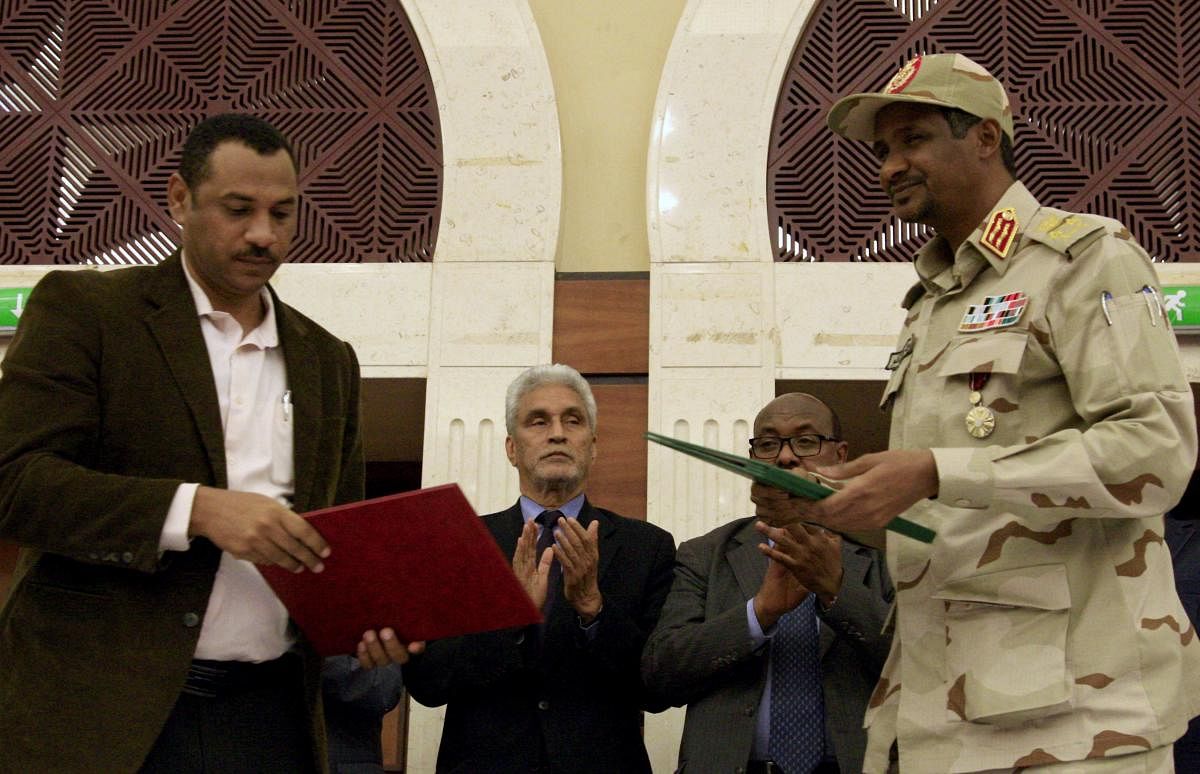 Sudanese deputy chief of the ruling miliary council Mohamed Hamdan Dagalo (R) and protest movement Alliance for Freedom and Changes leader Ahmad al-Rabiah stand after inking an agreement. Photo credit: AFP