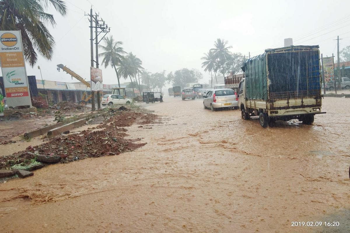 Vehicles wade through a flooded road following heavy showers in Malur, Kolar district, on Saturday. The town received 64 mm of rain.