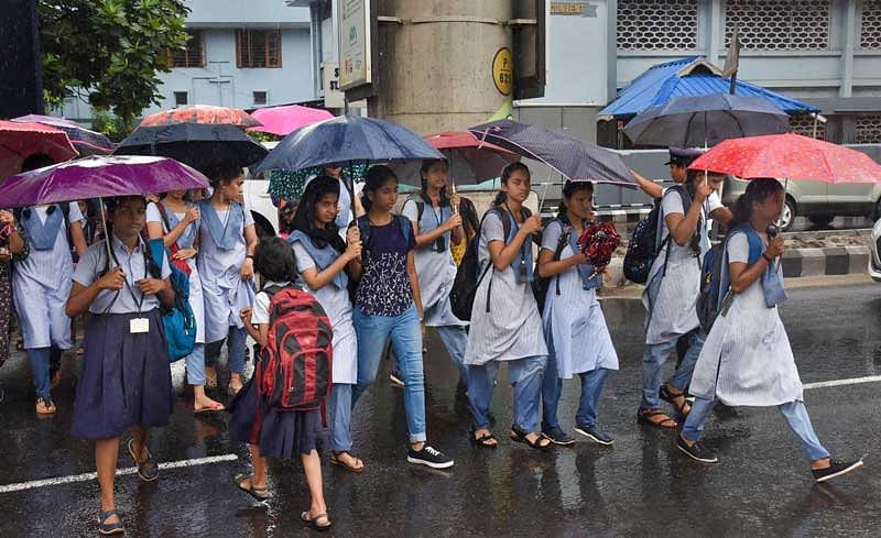 Students cross a road during monsoon rainfall, in Kochi. (PTI Photo)