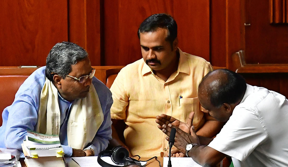 Congress Legislature Party leader Siddaramaiah speaks to Chief Minister H D Kumaraswamy in Legislative Assembly on Thursday. Chief Whip of the government Ganesh Hukkeri looks on. DH photo