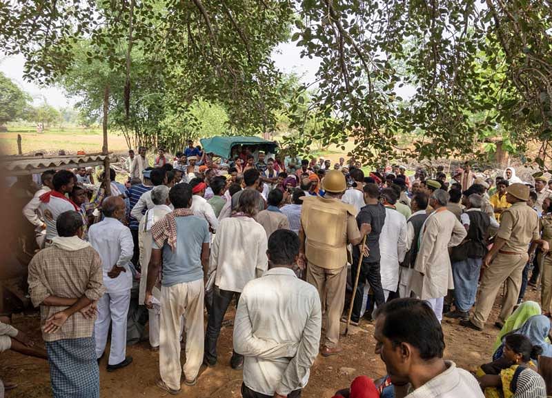 Villagers gather at the site where 10 people were gunned down over a property dispute in Sonbhadra district. (PTI Photo)