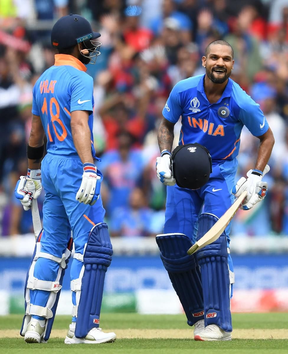India's Shikhar Dhawan (R) celebrates after scoring a century (100 runs) alongside India's captain Virat Kohli (L) during the 2019 Cricket World Cup group stage match between India and Australia at The Oval in London on June 9, 2019. (Photo by AFP)