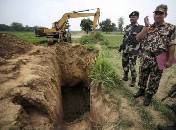 BSF men stand guard near opening of a tunnel that was found underneath the Indo-Pak border fence, some 300 mts inside the Indian Territory at Chachwal Samba about 70 km from Jammu - PTI