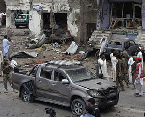 Pakistani security officials and rescue workers examine the site of car bombing on the outskirts of Peshawar, Pakistan, Sunday, June 2013. A car bomb exploded as a convoy of paramilitary troops passed through the outskirts of the northwest Pakistani city of Peshawar, killing more than a dozen people and wounding scores of others, police said. AP Photo