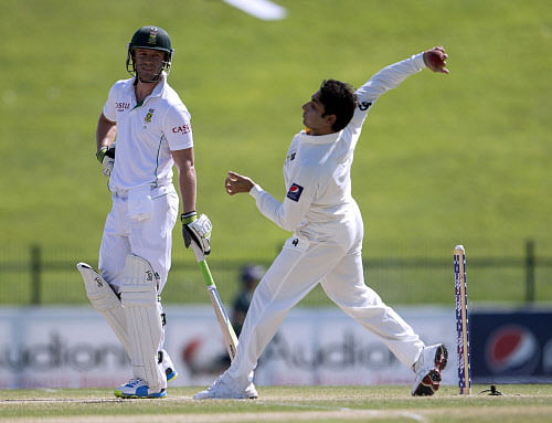 Pakistan's Saeed Ajmal bows as South Africa's batsman Ab de Villiers watches on the fourth day of their first Test against South Africa at the Sheikh Zayed Cricket Stadium in Abu Dhabi on October 17, 2013. AB de Villiers hit a fighting fifty to delay Pakistan's victory march over South Africa on the fourth day of the first Test in Abu Dhabi today. AFP PHOTO