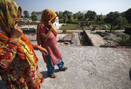 Village women inspect the damage caused on their home, allegedly by firing and shelling from the Pakistan side of the border on Friday night, in Rangpura village,  Jammu. Ap File Photo