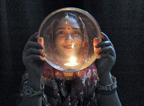 A married woman looks at the moon through a sieve before breaking her fast during 'Karva Chaut' celebrations in Mirzapur on Tuesday. PTI Photo