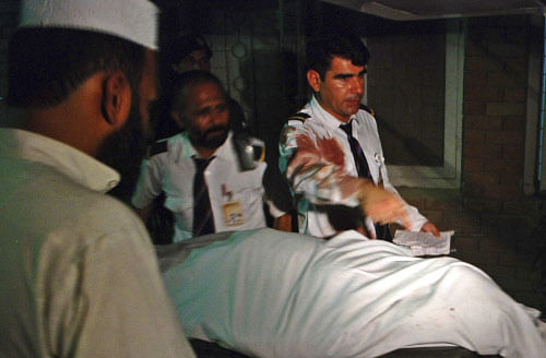Crew members of a Pakistan International Airlines(PIA) plane are seen beside the body of a woman who was killed on board their aircraft, at a hospital in Peshawar early June 25, 2014. Reuters photo