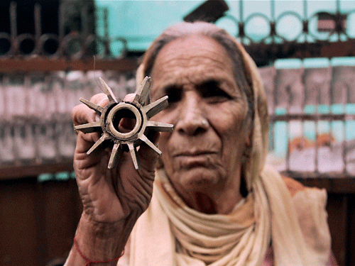 An elderly woman displays the mortar shell fired from the Pakistani side at Arnia in Jammu on Wednesday. PTI Photo