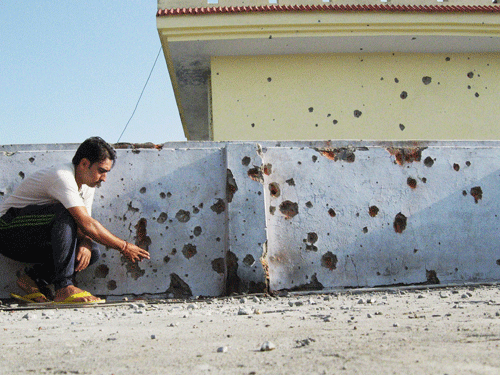 A man shows mortar shell marks on the wall of his house after shelling from the Pakistani side at Lalyal Camp Kanachak sector in Jammu on Thursday. PTI Photo