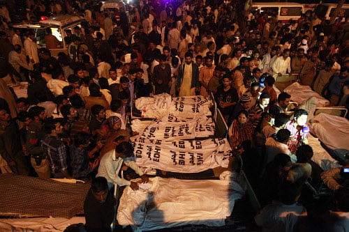 Pakistani relatives gather beside the covered bodies of victims who were killed in suicide bomb attack in Wagah border near Lahore November 2, 2014. At least 45 people were killed on Sunday when a suicide bomber blew himself up on the Pakistani-Indian border, police said, just after a daily ceremony when troops from both sides simultaneously lower the two nations' flags. REUTERS