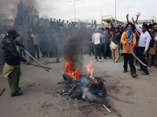 Enraged Christians residents burn men they suspected of being involved in bomb attacks on churches, after lynching them in Lahore. Reuters image