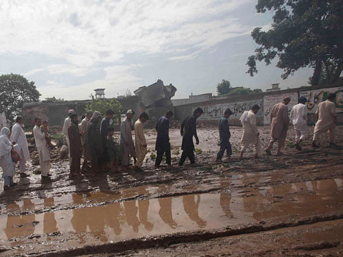 Residents walk along a muddy street after heavy rainfall caused flooding in Peshawar, Pakistan, July 27, 2015. Flash flooding caused by torrential monsoon rains has killed at least 28 in Pakistan and affected hundreds of thousands of people, according to aid agencies, with further downpours expected in the coming days. REUTERS