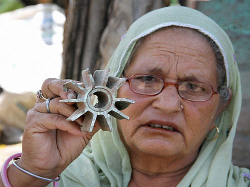 A woman shows part of a mortar shell allegedly fired from the Pakistan side at Abdullian village in R S Pura Sector, about 35 kms from Jammu on Friday. PTI Photo
