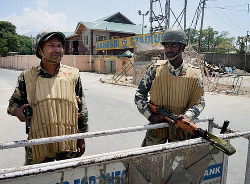 Security jawans stand guard outside Bakshi Stadium, the main venue for Independence day function, in Srinagar on Friday. Security has been beefed up around the Stadium. PTI Photo