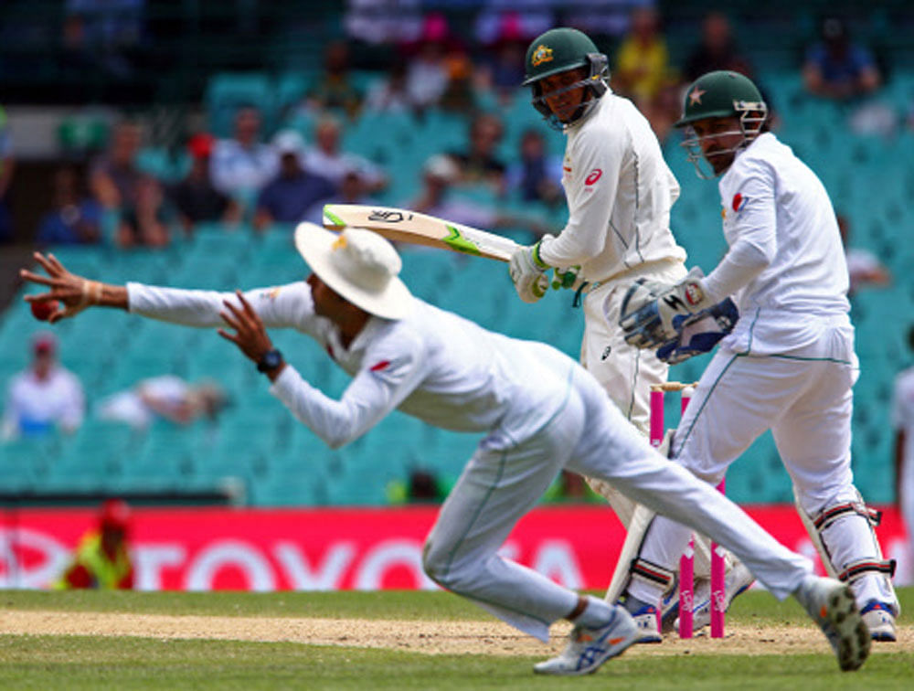 Australia's Usman Khawaja watches as Pakistan's Younis Khan dives to field the ball. REUTERS
