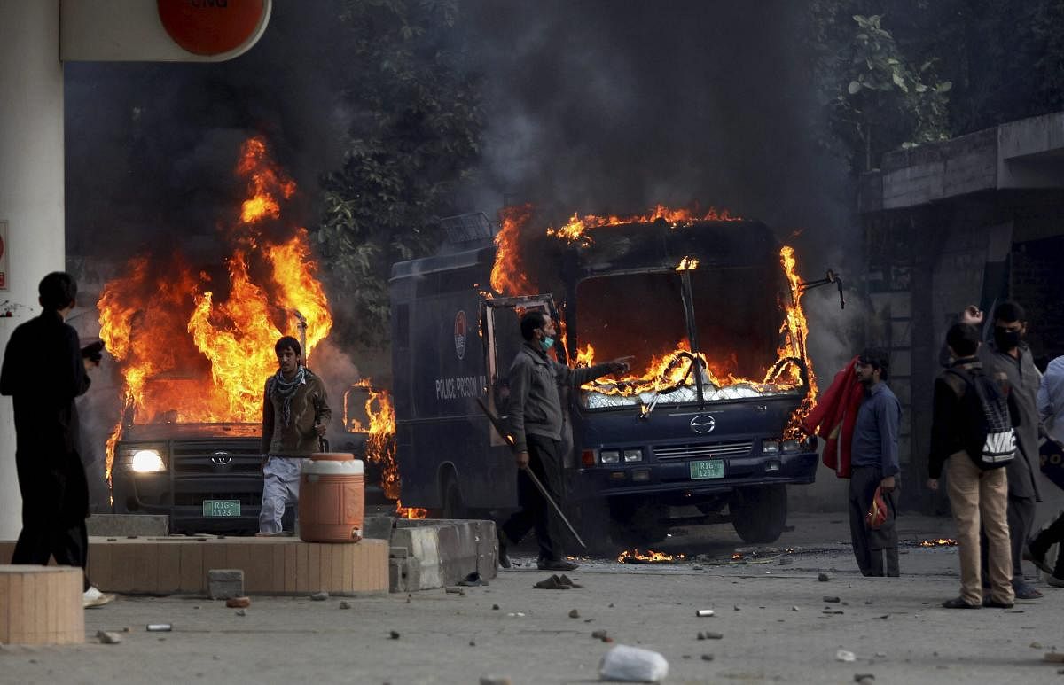Pakistani protesters gather next to burning police vehicles after setting on fire them during a clash in Islamabad, Pakistan, Saturday, Nov. 25, 2017. Pakistani police have launched an operation to clear an intersection linking capital Islamabad with the garrison city of Rawalpindi where an Islamist group's supporters have camped out for the last 20 days. AP/PTI