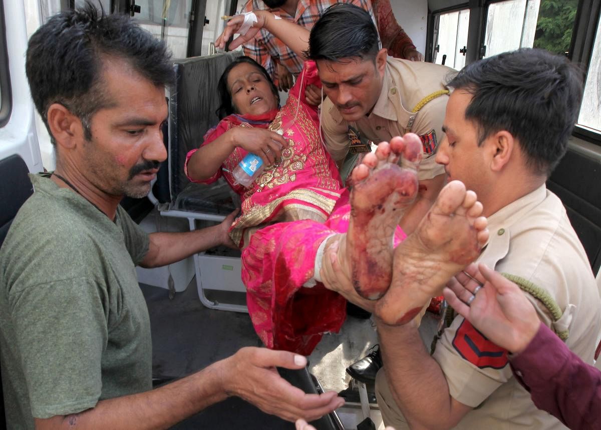 Volunteers and police personnel carry Sulakshana Devi, who was injured in cross border firing between Indian and Pakistan, into the Government Medical College Hospital in Jammu on Sunday. AFP