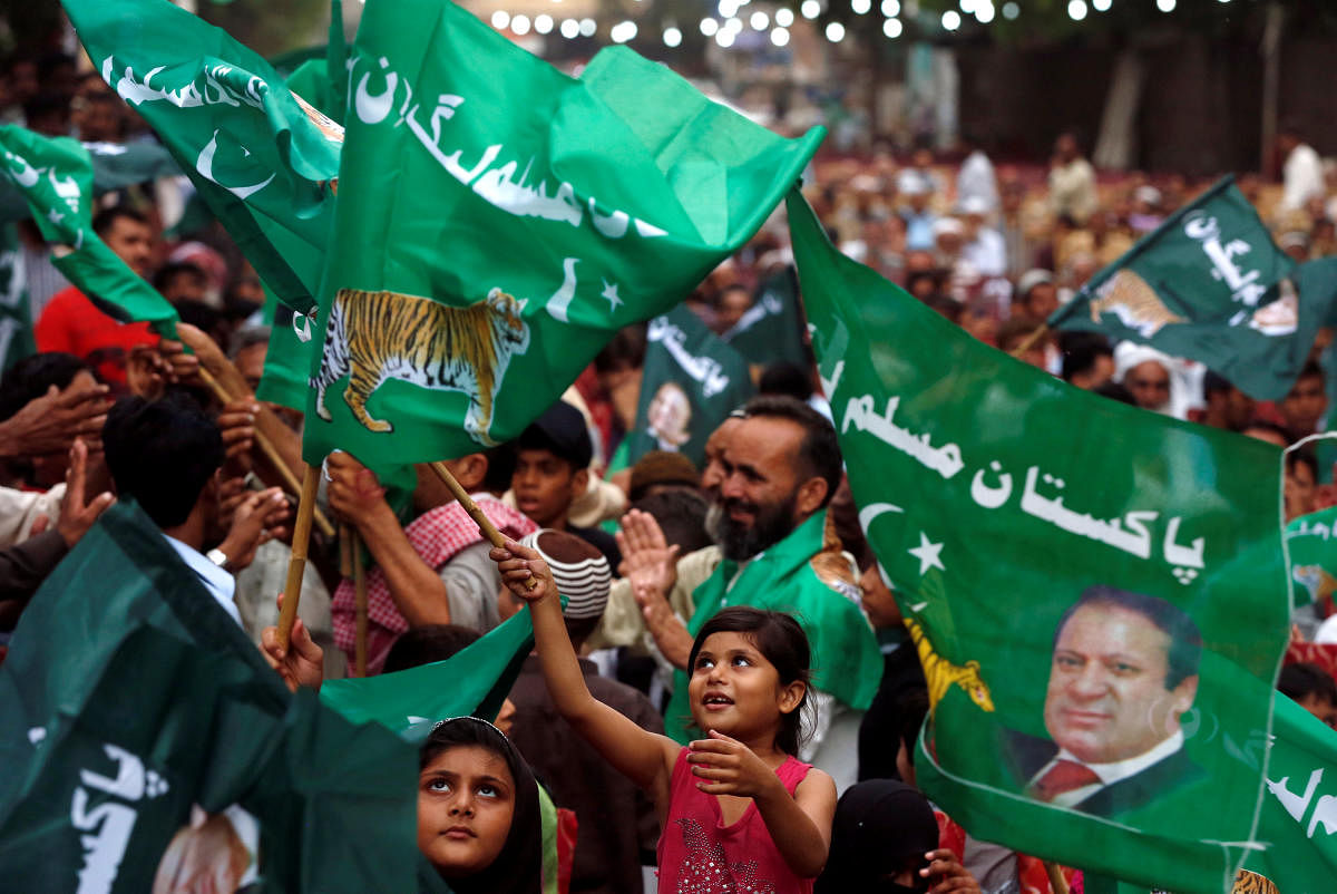 A child supporter of Shahbaz Sharif, brother of ex-prime minister Nawaz Sharif, and leader of Pakistan Muslim League - Nawaz (PML-N) waves party flags with others to welcome him during a campaign rally ahead of general elections in the Lyari neighborhood.