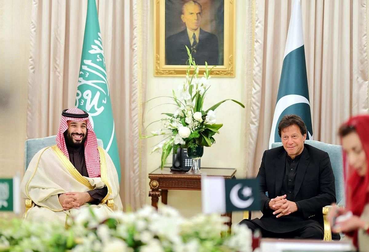 In this handout photograph released by Pakistan's Press Information Department (PID), Pakistan's Prime Minister Imran Khan and Saudi Arabian Crown Prince Mohammed bin Salman smile as they look at their delegation members during a signing of a MOU at the Prime Minister House in Islamabad. AFP/PID/Handout