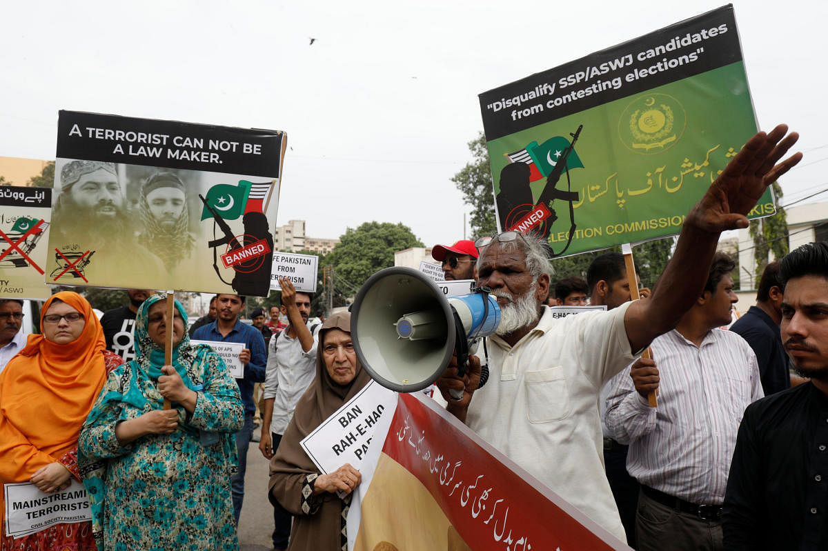 People hold signs as they chant slogans against the participation of banned outfits to take part in general elections, during a protest outside election commission office in Karachi. Reuters file photo.