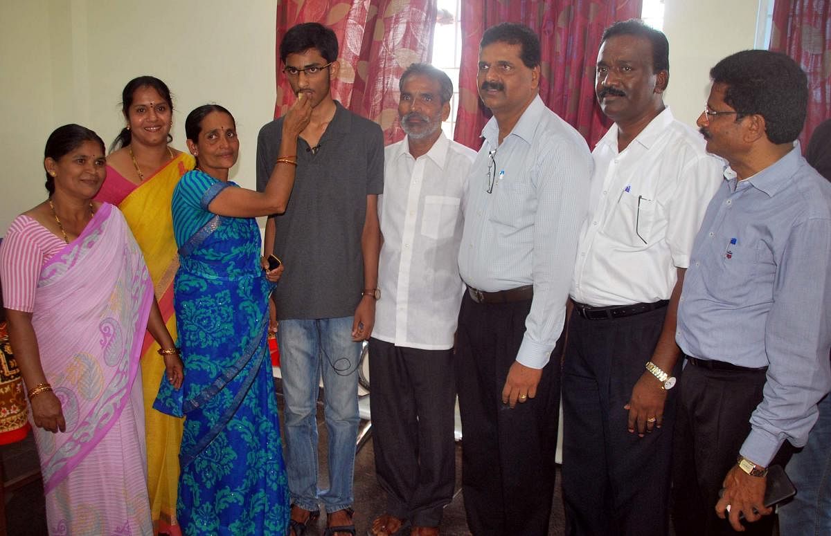 Parents offer sweets to H L Mohan Kumar, who excelled in PU exams, coming second in the state in Hassan on Monday.