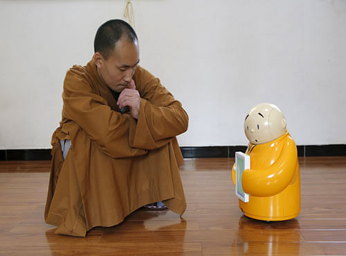 Master Xianfan looks at robot monk Xian'er as he demonstrates the robot's conversation function during a photo opportunity in Longquan Buddhist temple on the outskirts of Beijing. Reuters photo
