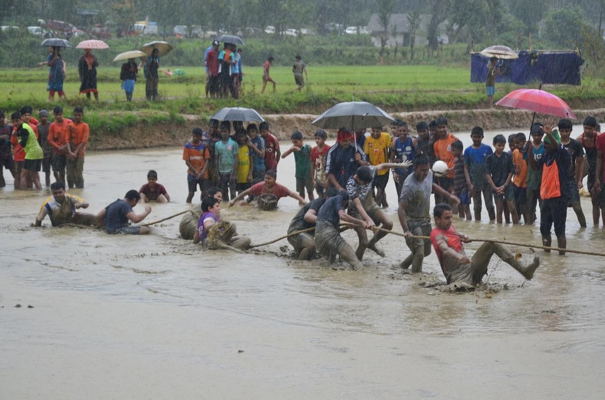 Schoolchildren take part in a tug-of-war competition amid rain at the state-level marshy field sports meet at Kaggodlu in Madikeri taluk on Saturday.