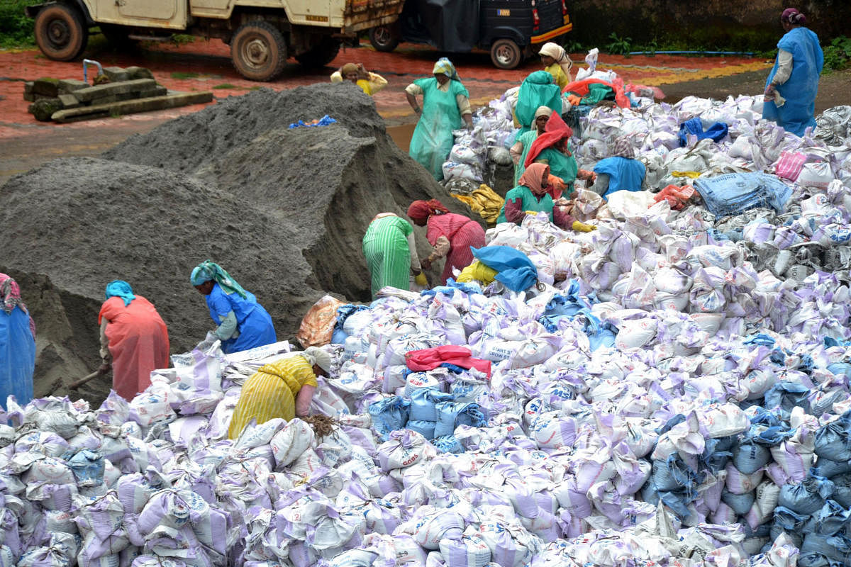 Workers fill sacks with manufactured sand, which will be used at the locations of landslides in Kodagu.