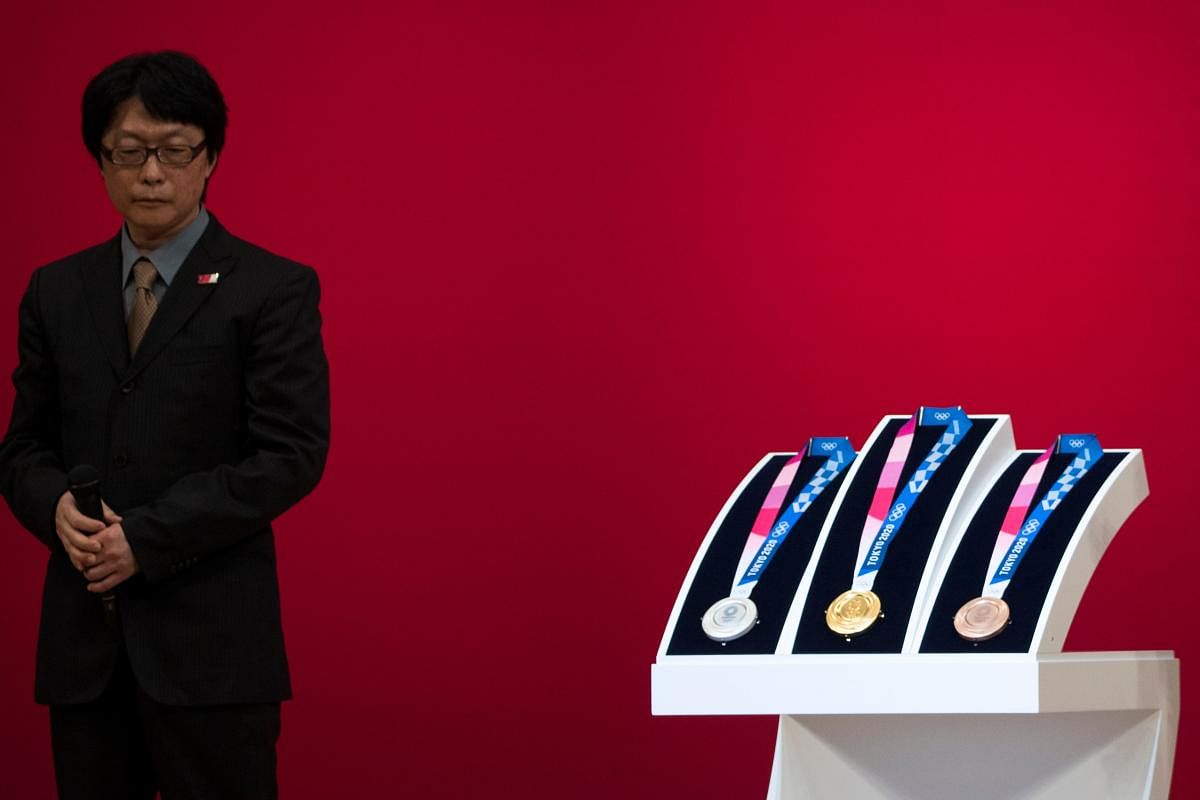 Junichi Kawanishi, the Japanese designer of the Tokyo 2020 Olympic Games medals, stands next to the medals after their unveiling during a ceremony marking one year before the start of the games in Tokyo (AFP Photo)