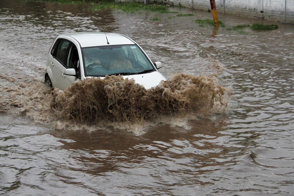 Vehicles ply on a waterlogged street following heavy monsoon rain in Jammu. Photo credit: PTI