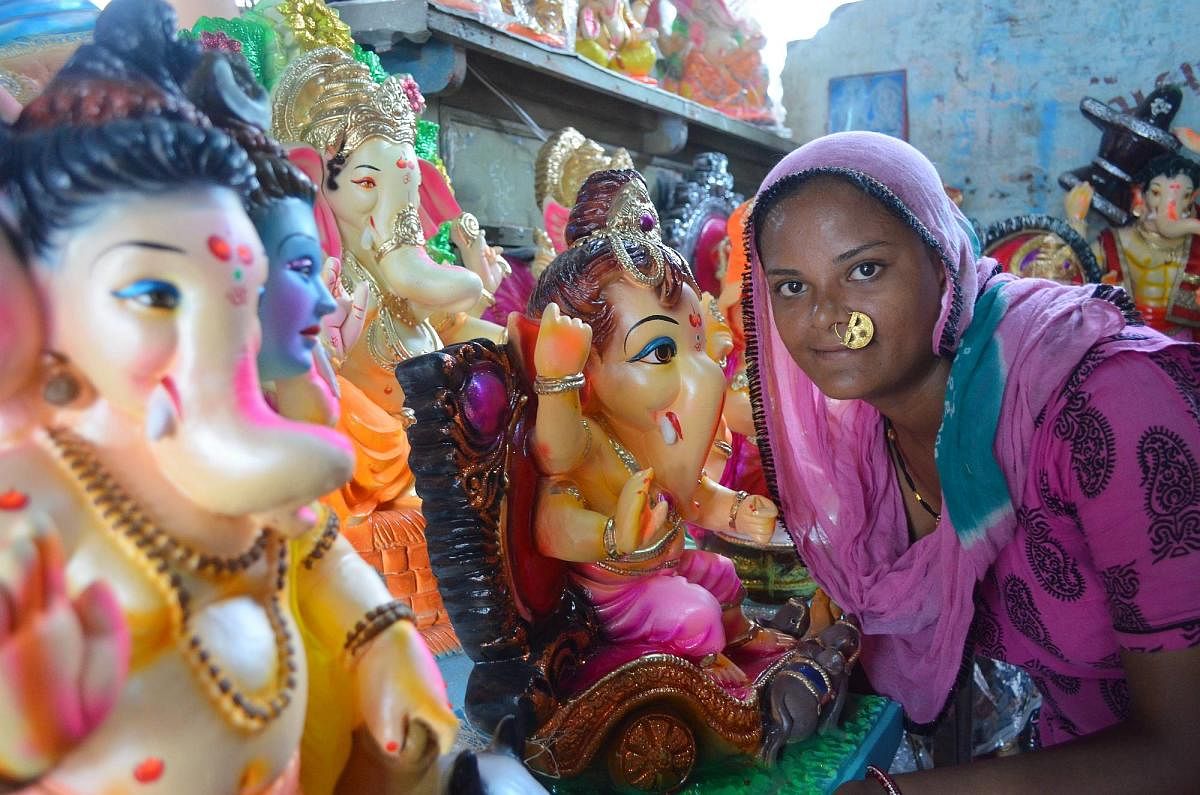 VIBRANT A woman of the Bawre tribe poses with idols of Lord Ganesha painted by them during Ganesh Chaturthi. PHOTOS BY AUTHOR