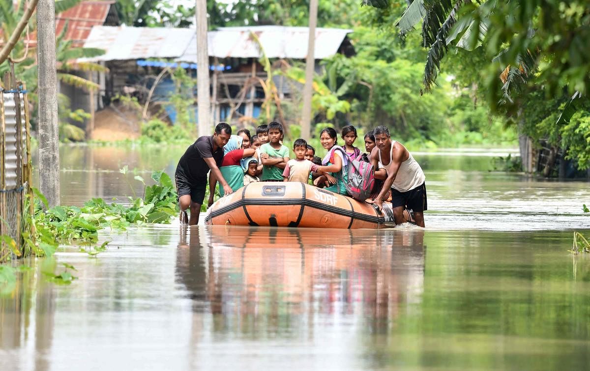 State Disaster Response Fund (SDRF) personnel rescue villagers on a boat from the flood-affected area of Jamguri village in Barpeta district of Assam. (Photo by Biju BORO / AFP)