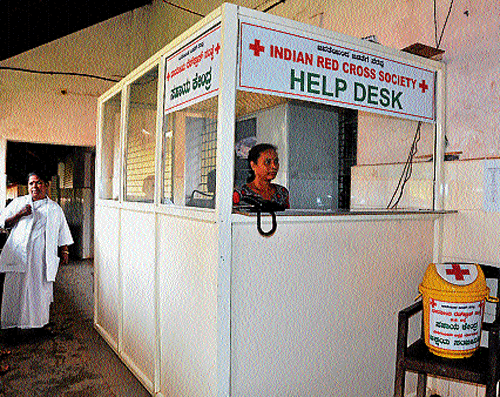 Help Desk Attendant Yashoda at the counter at the entrance of Lady Goschen hospital in Mangalore on Tuesday. A bucket meant for dropping unused medicines is also seen. DH photo