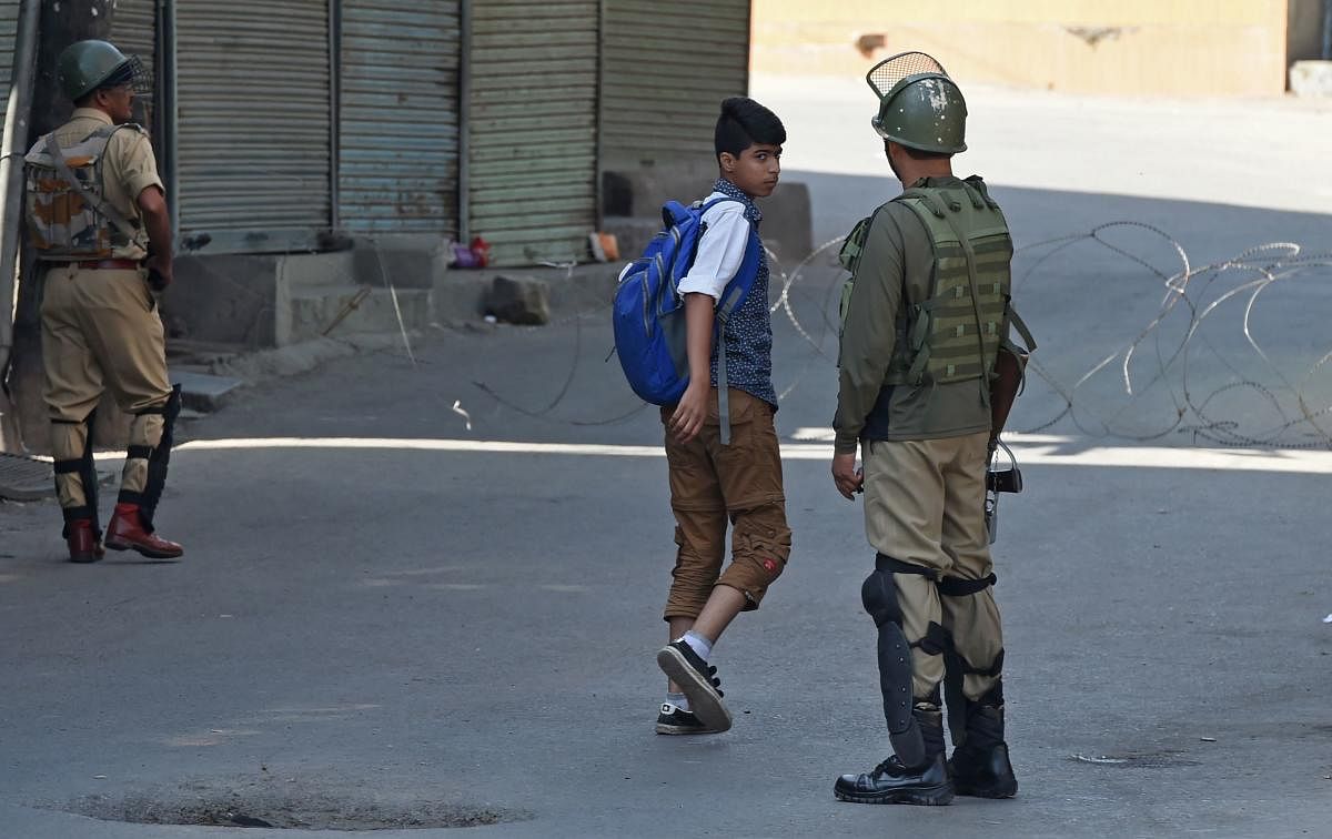Security forces question a Kashmiri boy during the first day of a strike called by Kashmiri separatists against attempts to revoke articles 35A and 370 of the state constitution, in Srinagar. AFP