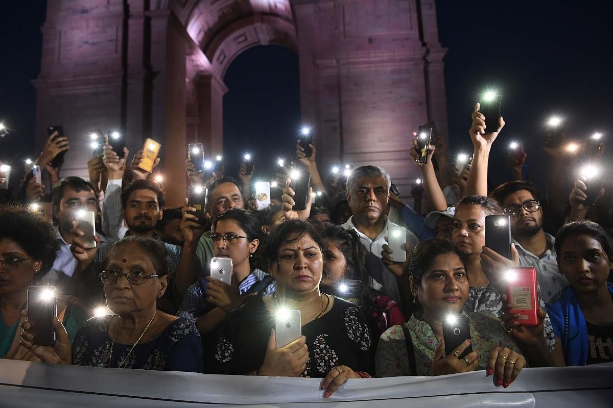 Indian social activists uses their mobile light as they take part in a solidarity rally in front of India Gate monument for the Unnao rape victim in New Delhi on July 29, 2019. ( AFP)