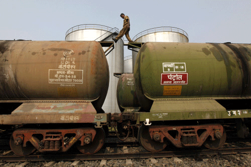 A worker walks atop a tanker wagon to check the freight level at an oil terminal on outskirts of Kolkata. Reuters
