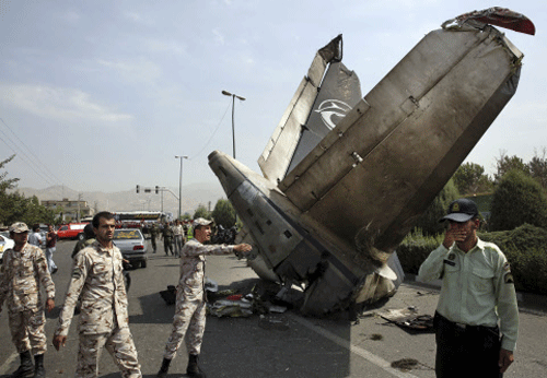 Iranian Revolutionary Guards and police officers inspect the site of a passenger plane crash near the capital Tehran, Iran, Sunday, Aug. 10, 2014. AP photo