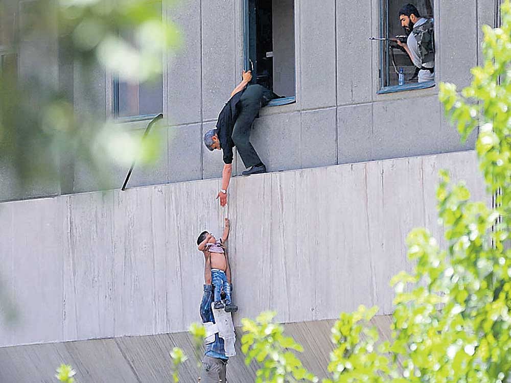 Iranian policemen evacuate a child from the parliament building in Tehran on Wednesday. AFP