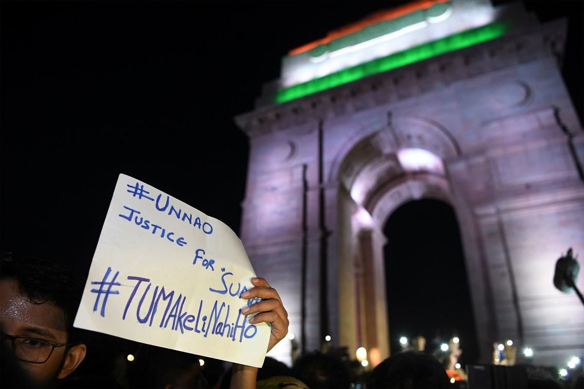 Indian social activists uses their mobile light as they take part in a solidarity rally in front of India Gate monument for the Unnao rape victim in New Delhi on July 29, 2019.(Photo by AFP)