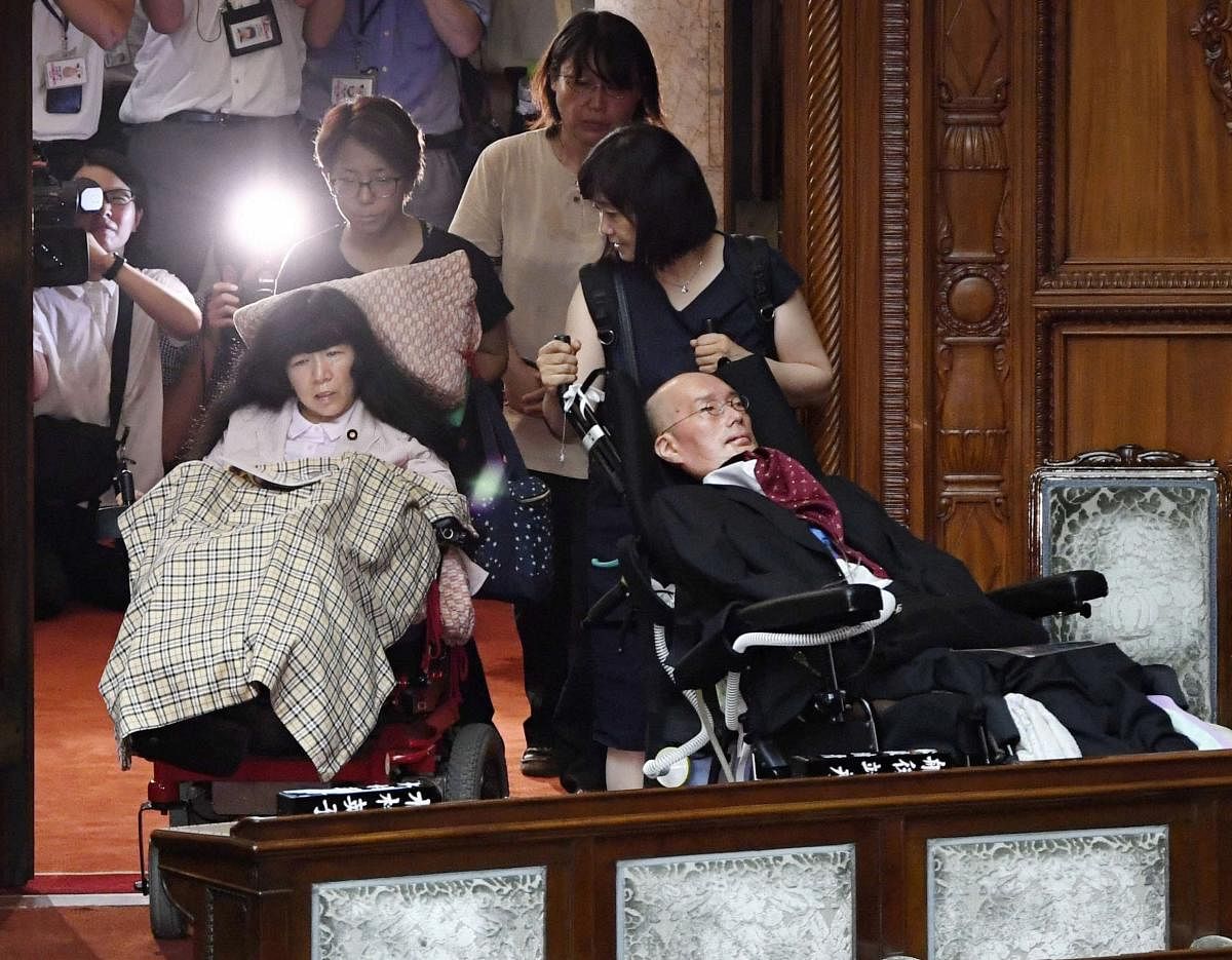 Two newly-elected wheelchair-bound lawmakers, Yasuhiko Funago, right, and Eiko Kimura are helped to arrive for an extraordinary session of the parliament's upper house in Tokyo  (AP/PTI)