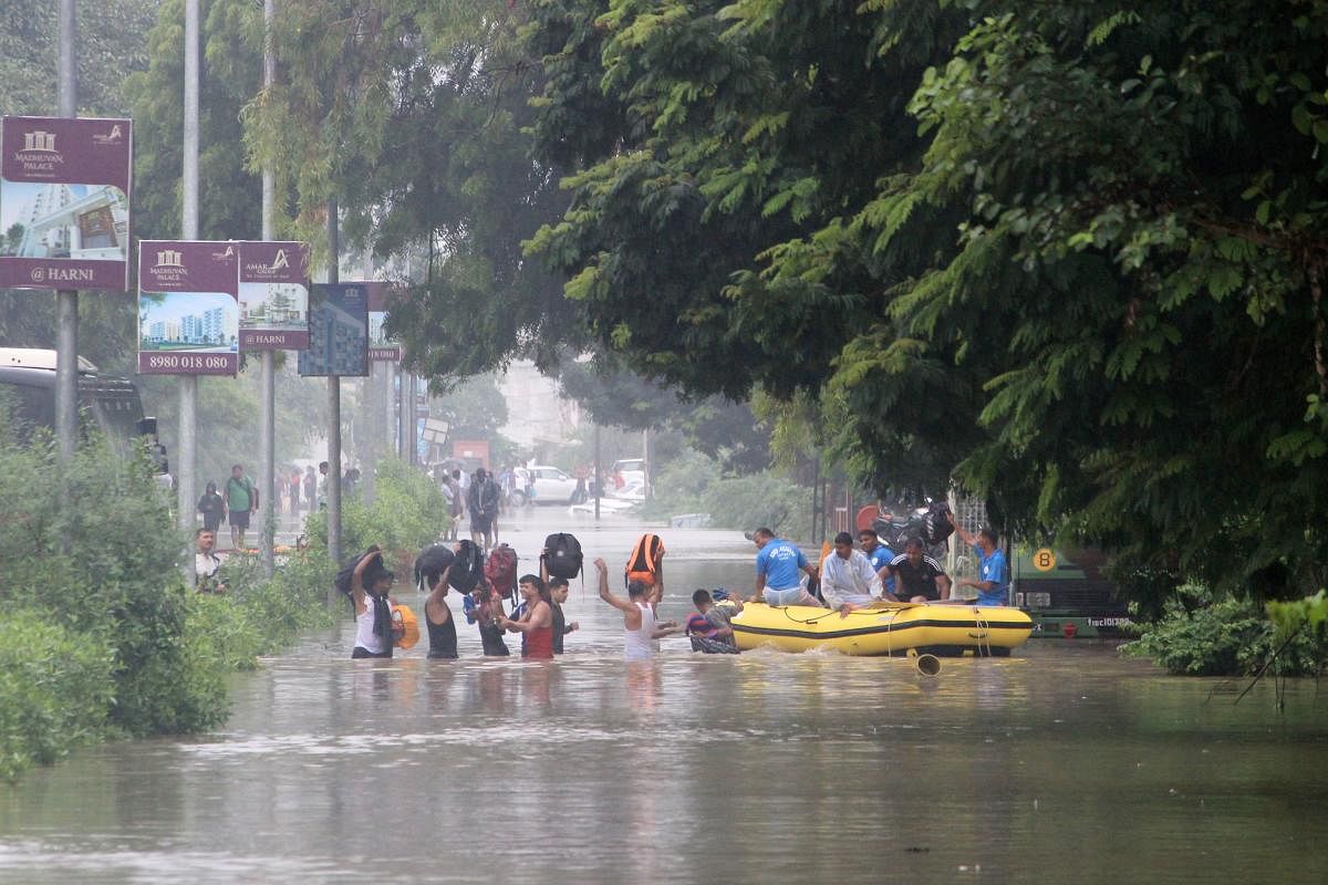 People wade in floodwaters to board a rescue boat of the Disaster Response Force (DRF) of the Gujarat state, in Vadodara, some 110 kms from Ahmedabad on August 1, 2019. (Photo by AFP)