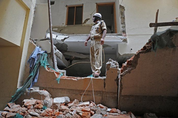 (Above) Fire and Emergency Services personnel at the building collapse site at Hutchins Road last month. NDRF team helps recover bodies from the debris. DH PhotoS/Pushkar V